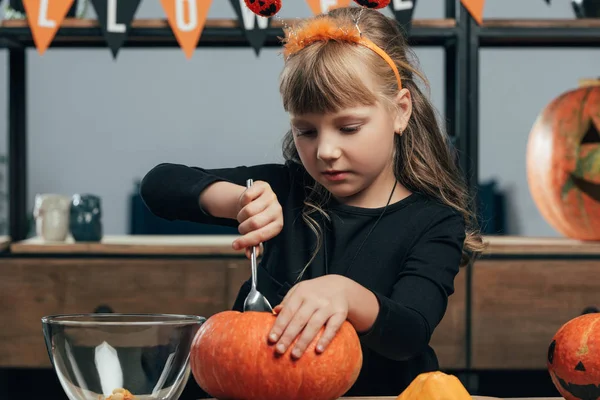 Portrait of little child carving pumpkin for halloween alone at tabletop at home — Stock Photo