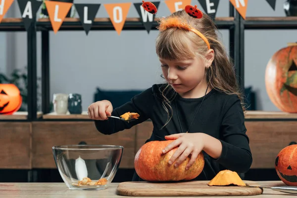 Portrait of cute kid carving pumpkin for halloween alone at tabletop at home — Stock Photo