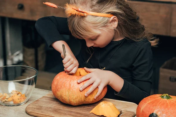 Cute kid carving pumpkin for halloween alone at tabletop at home — Stock Photo