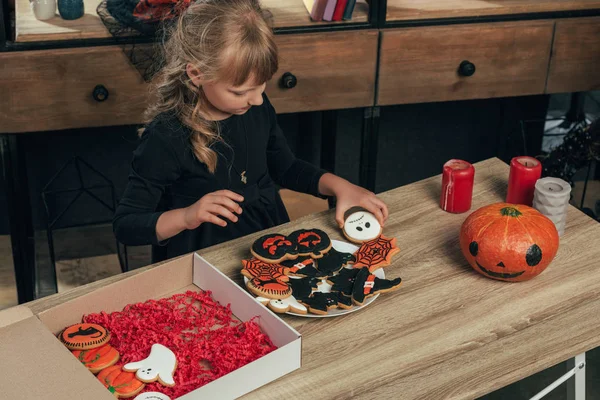Високий кут зору маленької дитини, що влаштовує печиво на Хеллоуїн на тарілці вдома — стокове фото