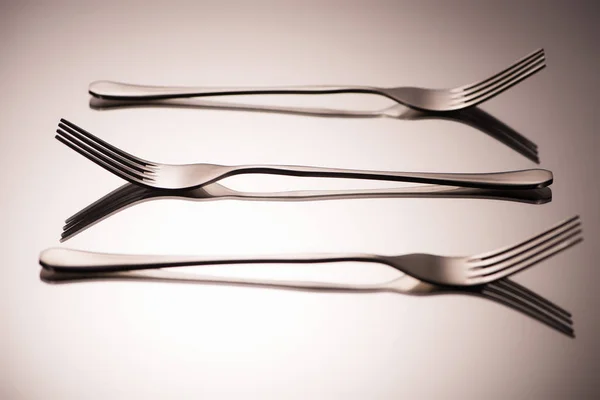 Close-up view of three arranged shiny forks reflected on grey — Stock Photo