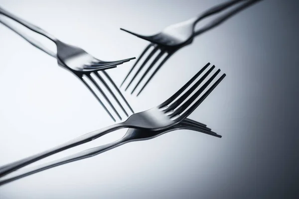 Close-up view of three shiny forks reflected on grey — Stock Photo