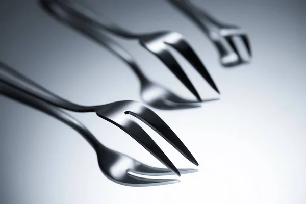 Close-up view of forks with two tines reflected on grey — Stock Photo