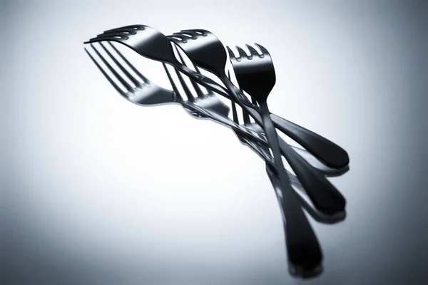 Close-up view of set of shiny metal forks reflected on grey — Stock Photo