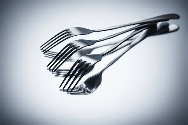 Close-up view of set of shiny metal forks on grey — Stock Photo