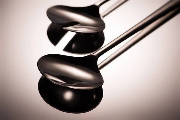 Close-up view of shiny stainless steel ladles reflected on grey — Stock Photo