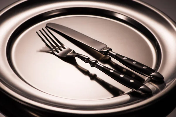 Close-up view of fork and knife on shiny metal tray on grey — Stock Photo