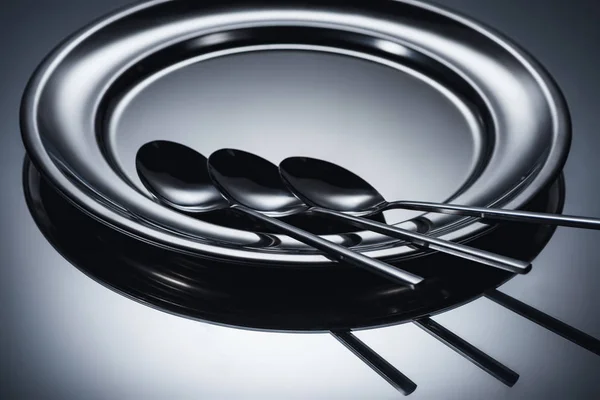 Vista de cerca de tres cucharas dispuestas en placa brillante en gris - foto de stock