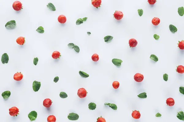 Vue de dessus des fraises mûres avec des feuilles de menthe sur le dessus de table blanc — Photo de stock