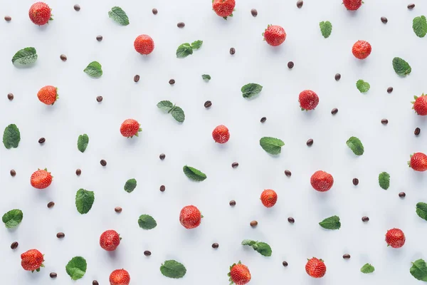 Vista superior de fresas maduras con hojas de menta y granos de café sobre una mesa blanca - foto de stock