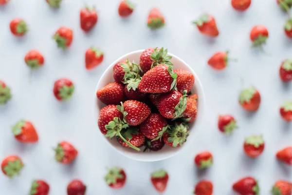 Vista superior del tazón de fresas frescas enteras sobre la mesa blanca - foto de stock
