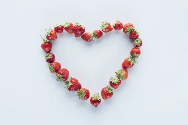 Top view of heart shape sign made of fresh strawberries on white surface — Stock Photo