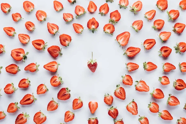 Rundrahmen halbierter reifer Erdbeeren mit Ganzem in der Mitte auf weißer Oberfläche — Stockfoto