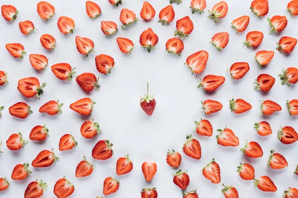 Top view of round frame of halved ripe strawberries with whole in middle on white surface — Stock Photo