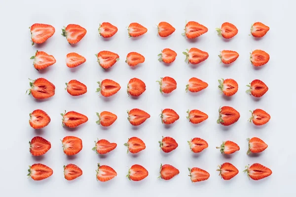 Vista superior da composição de morangos maduros cortados pela metade na superfície branca — Fotografia de Stock