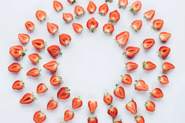Vue de dessus du cadre rond de fraises coupées en deux sur la surface blanche — Photo de stock