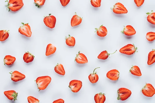 Vue de dessus des fraises coupées en deux juteuses sur la surface blanche — Photo de stock