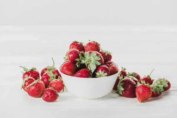 Close-up shot of bowl of strawberries on white wooden tabletop — Stock Photo