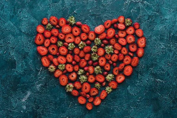 Top view of heart sign made of ripe strawberries on blue concrete surface — Stock Photo