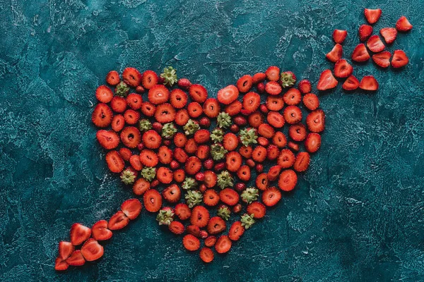 Vue du haut du cœur percé d'un panneau de flèche en fraises sur une surface en béton bleu — Photo de stock