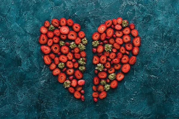 Draufsicht auf halbiertes Herzschild aus Erdbeeren auf blauer Betonoberfläche — Stockfoto