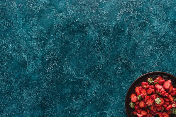 Vista superior del tazón con fresas maduras en la superficie de hormigón azul - foto de stock