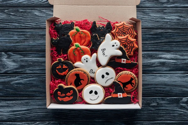 Elevated view of cardboard box with homemade halloween cookies on wooden table — Stock Photo