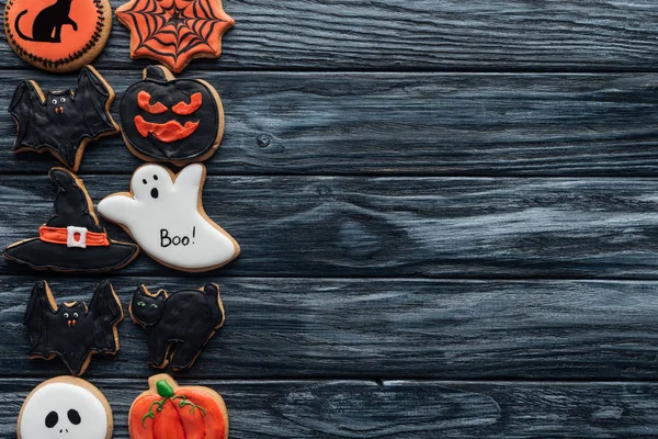 Vista elevada de biscoitos caseiros arranjados halloween colocados em fileiras sobre fundo de madeira preta — Fotografia de Stock