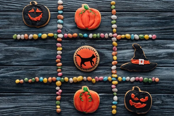 Vista superior de la composición de caramelos coloridos y galletas dispuestas de halloween en la mesa de madera - foto de stock