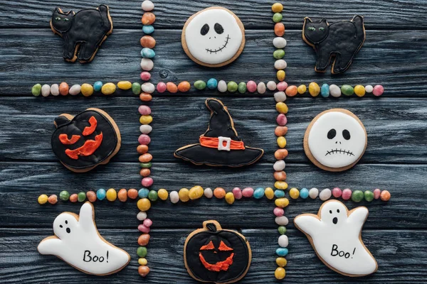 Vista superior da composição de doces coloridos e biscoitos de Halloween arranjados na mesa de madeira — Fotografia de Stock