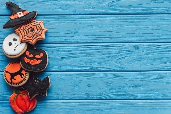 Top view of spooky homemade halloween cookies placed in row on blue wooden background — Stock Photo