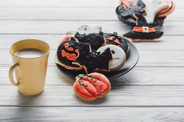 Plate with delicious halloween cookies and cup of milk on wooden table — Stock Photo