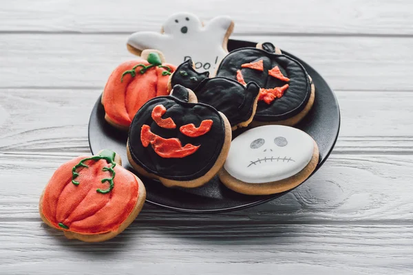 Close up view of plate with spooky halloween cookies on wooden table — Stock Photo