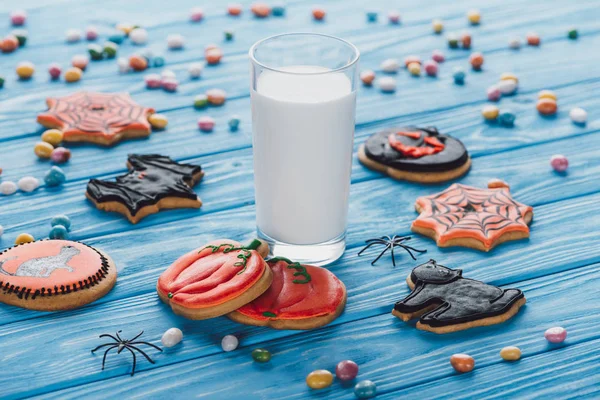 Close up view of candies, homemade halloween cookies and glass of milk on wooden table — Stock Photo