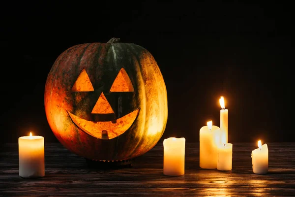 Scary jack o lantern with candles on wooden table on black background — Stock Photo