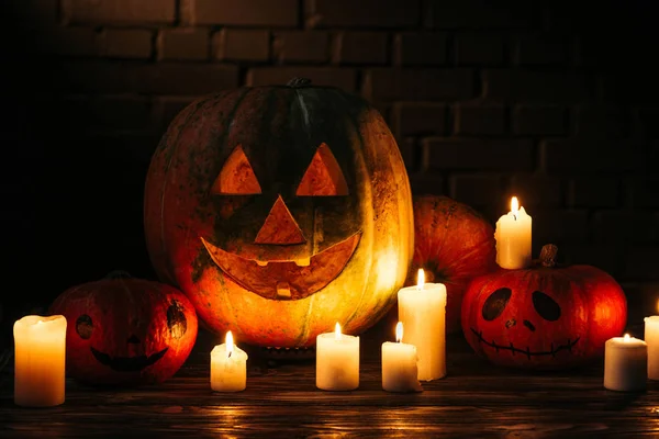 Citrouilles sculptées halloween sur une table en bois devant un mur de briques — Photo de stock