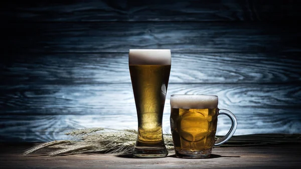 Dois copos de cerveja dourada e espiguetas de trigo na mesa de madeira, conceito oktoberfest — Fotografia de Stock