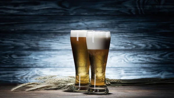 Fresh beer in glasses and wheat spikelets on wooden table, oktoberfest concept — Stock Photo