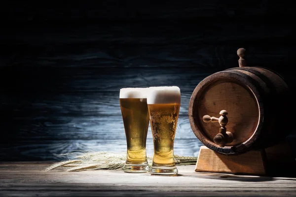 Fresh beer in glasses, wheat spikelets and beer barrel on wooden table, oktoberfest concept — Stock Photo