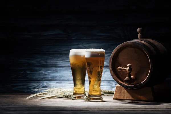 Two glasses of beer, wheat spikelets and beer barrel on wooden table, oktoberfest concept — Stock Photo