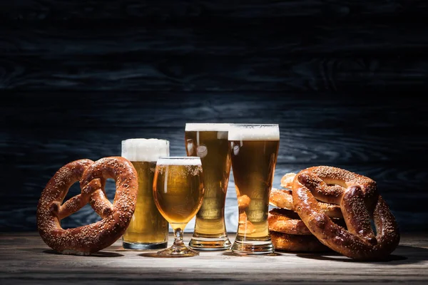 Ainda vida de copos de cerveja e pretzels saborosos na mesa de madeira, conceito oktoberfest — Fotografia de Stock