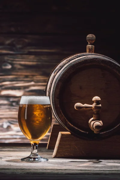 Glass of fresh beer and beer barrel on wooden table, oktoberfest concept — Stock Photo