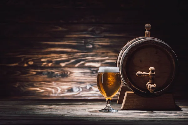 Glass of tasty beer and beer barrel on wooden table, oktoberfest concept — Stock Photo