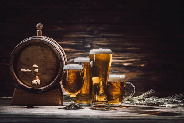 Cerveza en vasos, espiguillas de trigo y barril de cerveza en mesa de madera, concepto oktoberfest - foto de stock