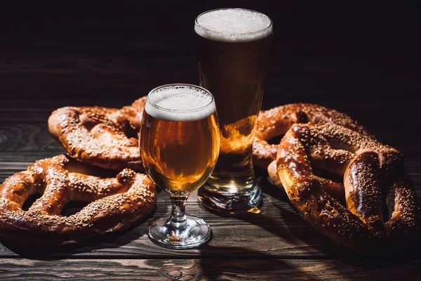 Dos vasos de cerveza y sabrosos bollos en mesa de madera, concepto oktoberfest - foto de stock