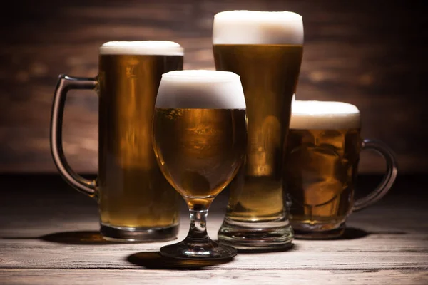 Quatro copos de cerveja saborosa na mesa de madeira, conceito oktoberfest — Fotografia de Stock