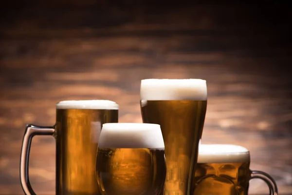 Quatro copos de cerveja saborosa no fundo de madeira, conceito oktoberfest — Fotografia de Stock