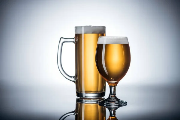 Dos vasos de cerveza sabrosa en la superficie reflectante, concepto oktoberfest - foto de stock