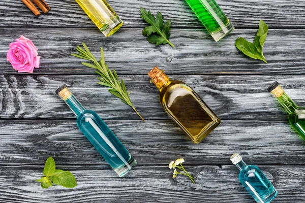 Set of colored bottles with natural herbal essential oils on wooden surface — Stock Photo