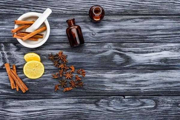 Flaschen mit natürlichen ätherischen Kräuterölen, Zimtstangen und Nelken auf dem Holztisch — Stockfoto